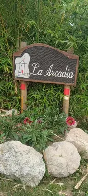 a sign sitting in the grass with rocks at La Arcadia in Mina Clavero