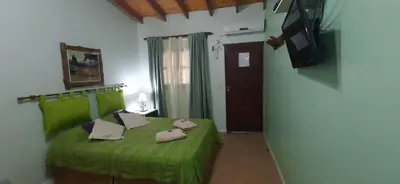 a bedroom with a green bed and a television at La Arcadia in Mina Clavero