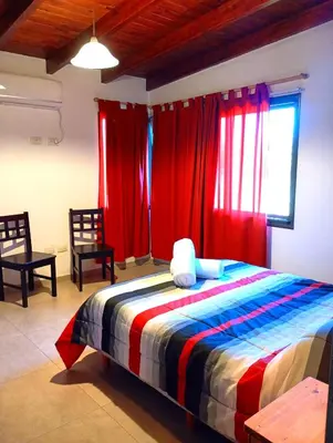 a bedroom with red curtains and a bed with two chairs at Brisas del Lago in La Estancia
