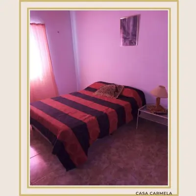 a bedroom with a bed with a striped blanket at CasaCarmela8 in Villa Carlos Paz