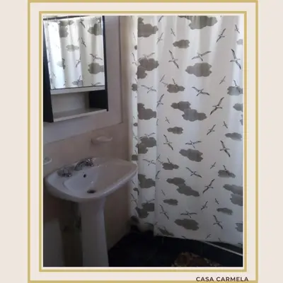 a bathroom with a sink and a shower curtain with clouds at CasaCarmela8 in Villa Carlos Paz