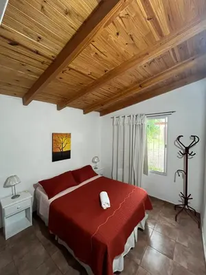 a bedroom with a red bed and a wooden ceiling at Cabaña brisas del lago in Villa Parque Siquiman