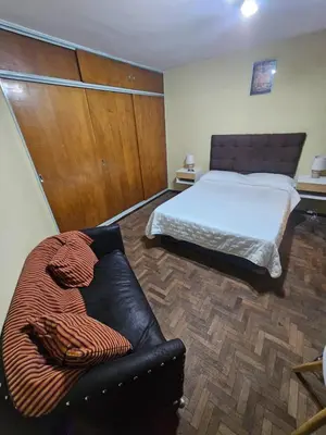 a bedroom with a bed and a leather couch at En la cañada cerca de todo in Cordoba