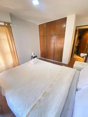 a bedroom with a large white bed with a wooden cabinet at LitStay Paraná in Cordoba