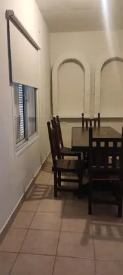 a dining room with a table and chairs and two windows at Complejo Bach in Villa Carlos Paz