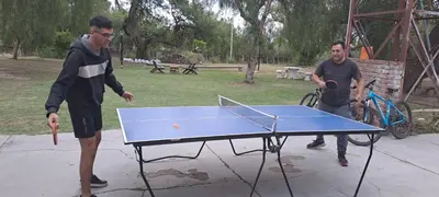 two men playing ping pong on a ping pong table at Posada Los Cerros in Luján