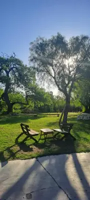 a picnic table and bench in a park with trees at Posada Los Cerros in Luján
