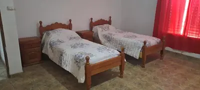 two twin beds in a room with red curtains at Posada Los Cerros in Luján