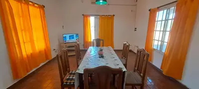 a dining room with a table with chairs and a television at Posada Los Cerros in Luján