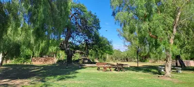 a picnic table and benches in a park with trees at Posada Los Cerros in Luján
