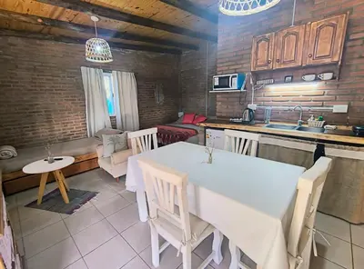 a kitchen and living room with a white table and chairs at Ares cabaña de campo- Rincón de Afrodita in San Lorenzo