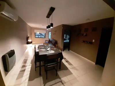 a dining room and living room with a table and chairs at Rincón de sol y rio in Villa Carlos Paz