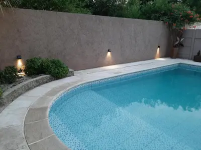 a swimming pool next to a concrete wall with lights at Rincón de sol y rio in Villa Carlos Paz