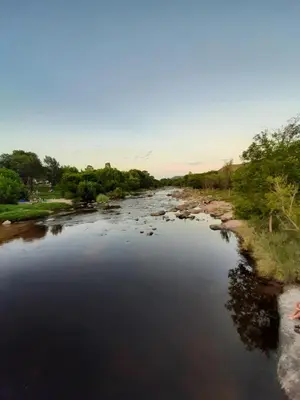 a river with rocks and trees in the distance at Rincón de sol y rio in Villa Carlos Paz