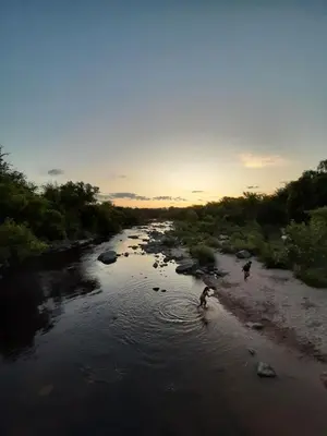 two people walking in a river at sunset at Rincón de sol y rio in Villa Carlos Paz