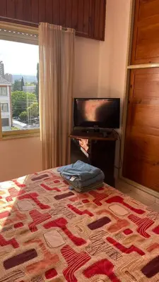 a bedroom with a bed and a television and a window at departamento moreno151 in Villa Carlos Paz