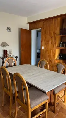 a dining room table with chairs and a wooden table at departamento moreno151 in Villa Carlos Paz