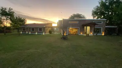 a house in a yard with the sun setting behind it at Casa de verano confortable in Villa de Las Rosas