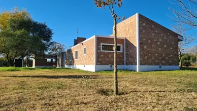 a brick building with a tree in a field at Casa de verano confortable in Villa de Las Rosas