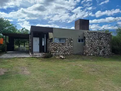 a stone house with a stone wall and a tower at Casa Despertares - Las Rabonas in Mina Clavero