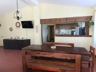 a dining room with a wooden table and a television at Silencio Dorado in Villa Serranita