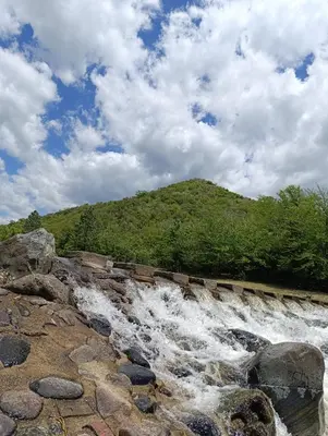 a river with water rushing over rocks and a hill at Silencio Dorado in Villa Serranita