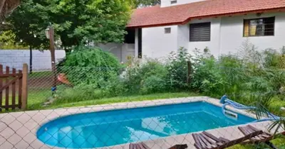 a swimming pool in a yard with a house at Cabañas La Petunia in Santa Rosa de Calamuchita