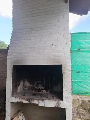a white brick fireplace with a bench in it at Cabañas La Petunia in Santa Rosa de Calamuchita
