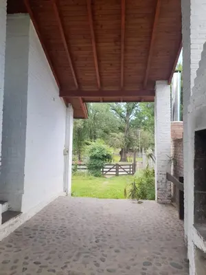 an open porch with a wooden roof with a view of a park at Cabañas La Petunia in Santa Rosa de Calamuchita