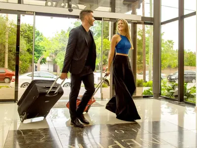 a man and a woman walking with a suitcase at Neper Hotel in Cordoba