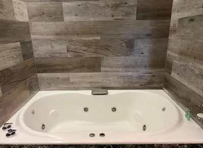 a white bath tub in a bathroom with wooden walls at Neper Hotel in Cordoba