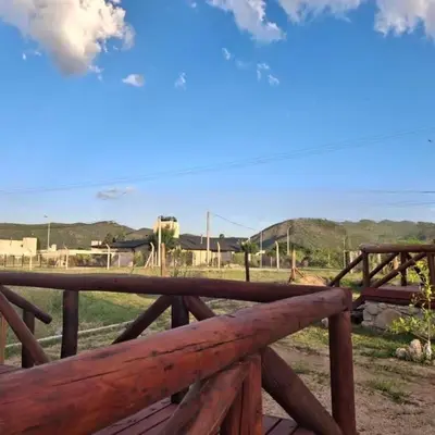 a wooden fence with a view of a farm at Cima Capri Cabañas in Villa Carlos Paz