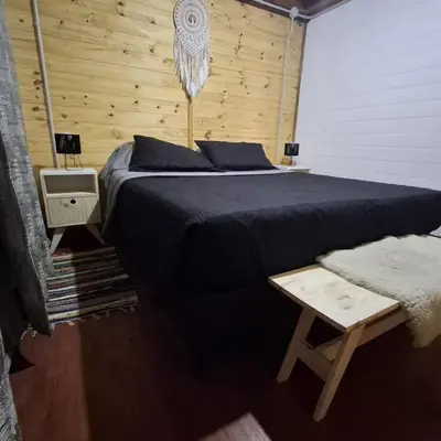 a bedroom with a large bed and a wooden wall at Cima Capri Cabañas in Villa Carlos Paz