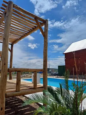 a wooden pergola next to a swimming pool at Cima Capri Cabañas in Villa Carlos Paz