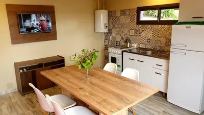a kitchen with a wooden table and white appliances at La Moradita Villa Carlos Paz in Villa Carlos Paz
