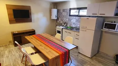 a kitchen with a wooden table and a refrigerator at La Moradita Villa Carlos Paz in Villa Carlos Paz