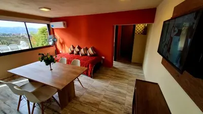a room with a red bed and a table and a window at La Moradita Villa Carlos Paz in Villa Carlos Paz