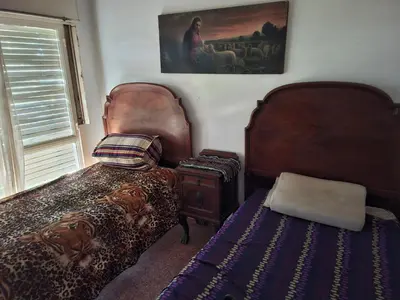 a bedroom with two beds next to a window at Chalet de Montaña a 8 cuadras del centro de Carlos Paz con pileta de 9 x 4 in Villa Carlos Paz