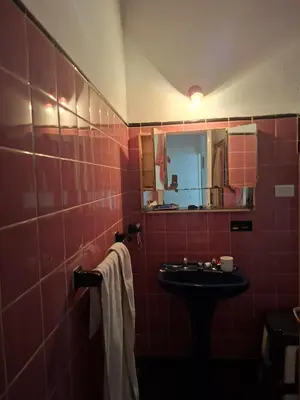 a red tiled bathroom with a sink and a mirror at Chalet de Montaña a 8 cuadras del centro de Carlos Paz con pileta de 9 x 4 in Villa Carlos Paz