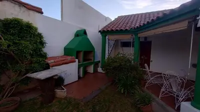 a green and white house with a bench in the yard at Acogedora Casa Familiar en Zona Residencial in Cordoba