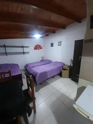 a bedroom with two beds and a table and chairs at Monoambiente Cerro in Villa Carlos Paz