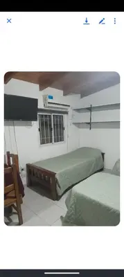 a bedroom with two beds and a chair and a window at Monoambiente Cerro in Villa Carlos Paz