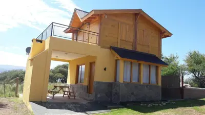 a house with a table in front of it at Cabañas El Conejo Negro in Villa Cura Brochero