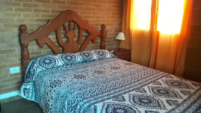 a bedroom with a bed with a blue and white quilt at Cabañas El Conejo Negro in Villa Cura Brochero