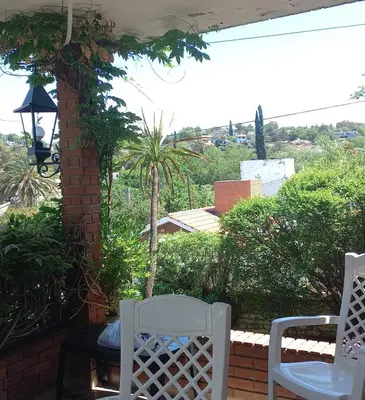 two white chairs and a table on a patio at Casa y cabaña de Gachy in Villa Carlos Paz