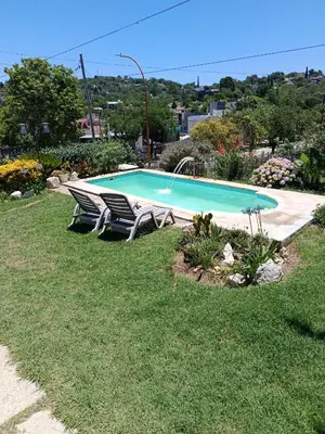 a swimming pool with two lounge chairs in the grass at Casa y cabaña de Gachy in Villa Carlos Paz