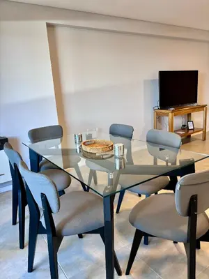 a dining room with a glass table and chairs at Departamento moderno y lujoso con gym y piscina in Cordoba