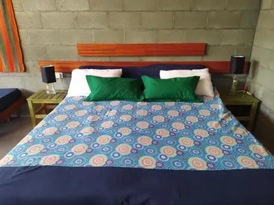 a bed with a blue comforter and green pillows at Sol de Los Nogales in Merlo