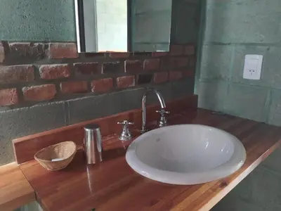 a white sink in a bathroom with a brick wall at Sol de Los Nogales in Merlo