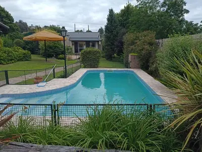 a swimming pool in a yard with an umbrella at Champ Cervi in San Antonio de Arredondo